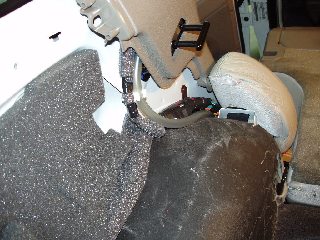 Car interior with the carpet lifted to show the foam sound deadening and felt padding underneath