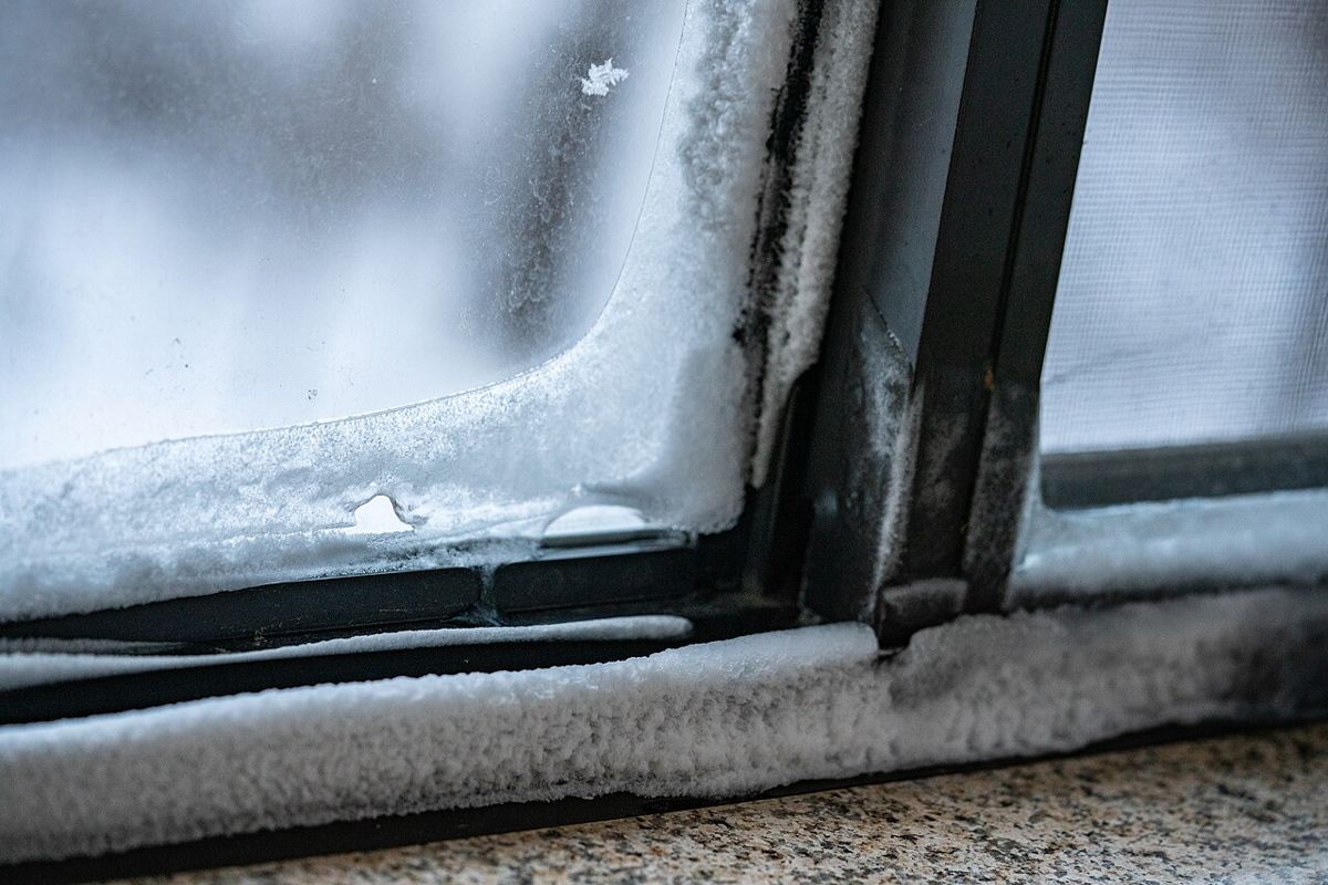 Eis und Frost an der Innenseite eines Fensterrahmens und einer Fensterbank in einem Haus in Minneapolis im Winter