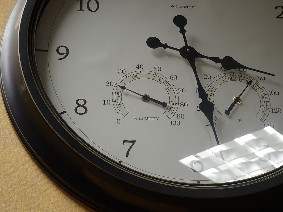 Wanduhr mit eingebautem Hygrometer, das in einem beheizten Gebäude im Winter unter 20 Prozent relative Luftfeuchtigkeit anzeigt