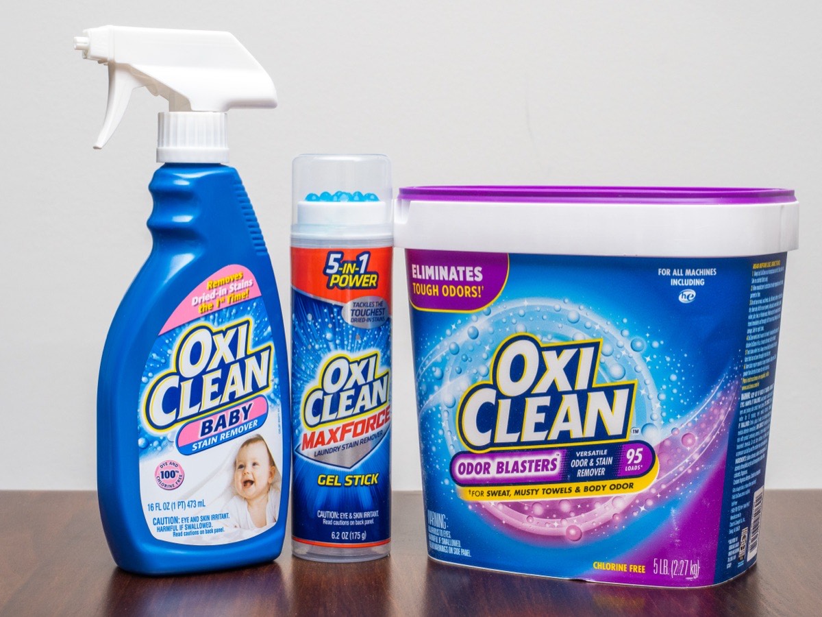 Spray détachant, stick en gel et pot de poudre à l’oxygène actif de la marque OxiClean sur une table