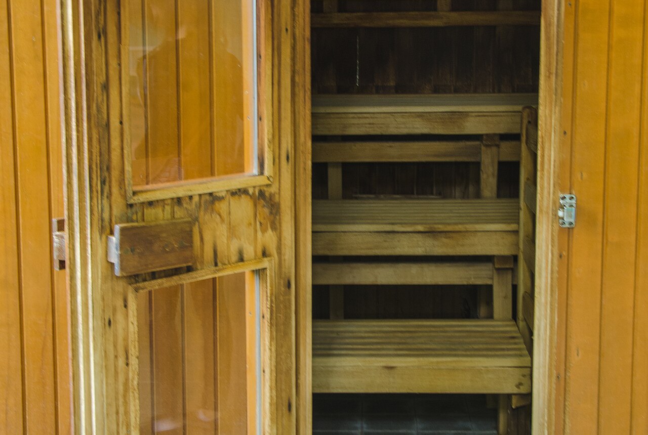 El interior de madera de una sauna pública, con bancos escalonados y una estufa