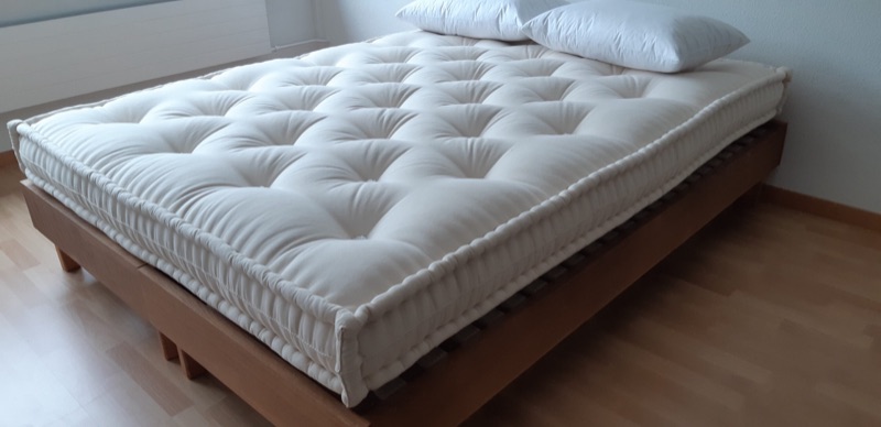 Matelas Cardelaine en laine et latex naturel, capitonné à la main, posé sur un lit en bois