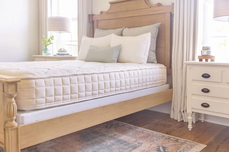 Naturepedic Chorus organic mattress on a carved wooden bed in a bright bedroom